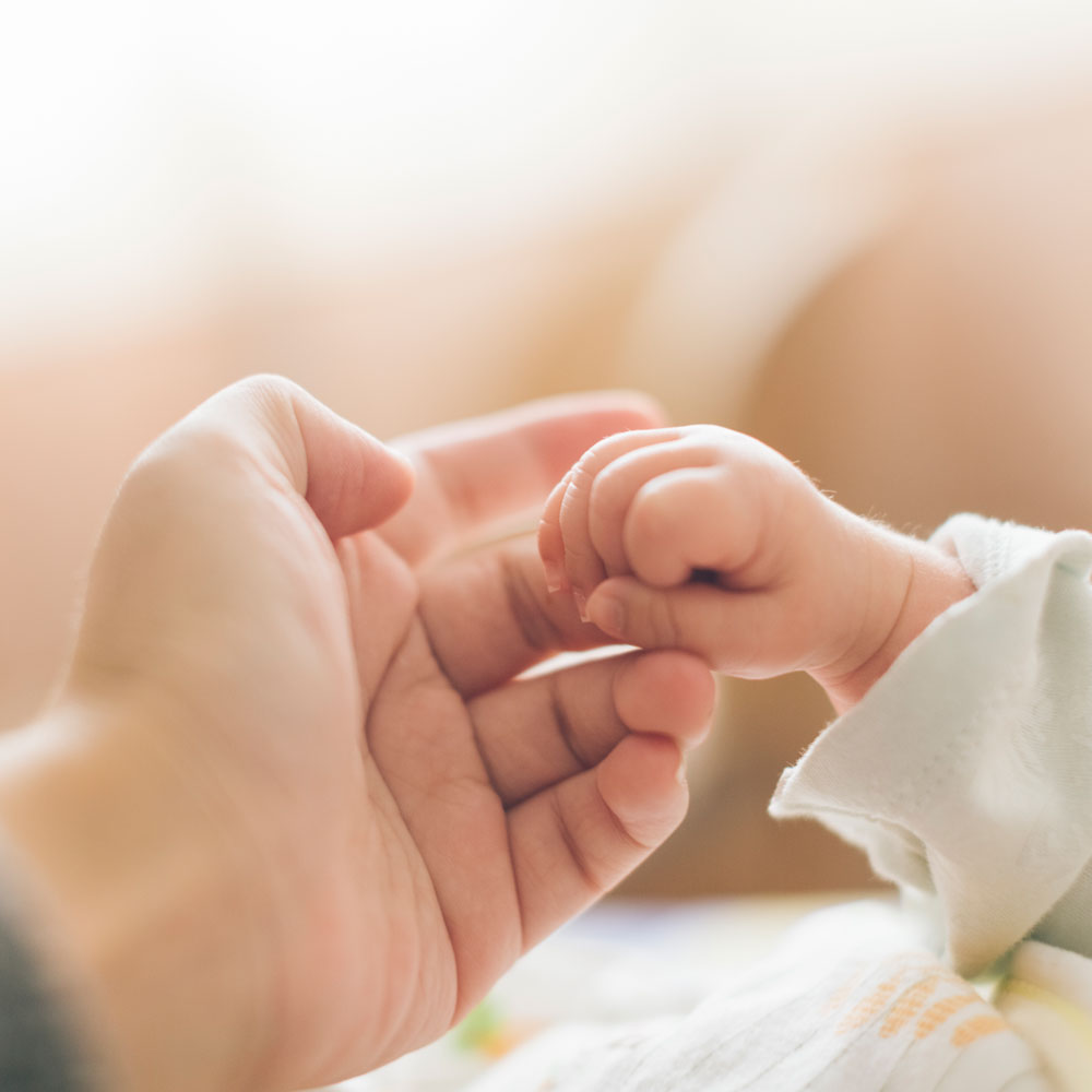 Hand of newborn around hand of Mom